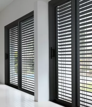 brise soleil orientable. Volets gris ouverts, laissant entrer la lumière extérieure, filtrée par les lames horizontales, dans une pièce lumineuse aux murs blancs et au sol brillant.