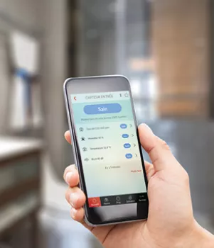 Un smartphone affiche des données de santé, tenu par une main, dans un environnement intérieur flou.