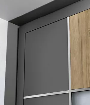 Un placard moderne avec des portes en bois et métal gris, placé dans un angle de pièce, donnant un aspect contemporain.