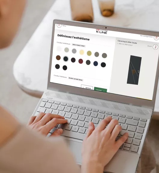 Ordinateur portable affichant une interface de personnalisation de couleurs pour portes, utilisé par une personne dans un environnement de bureau moderne.
