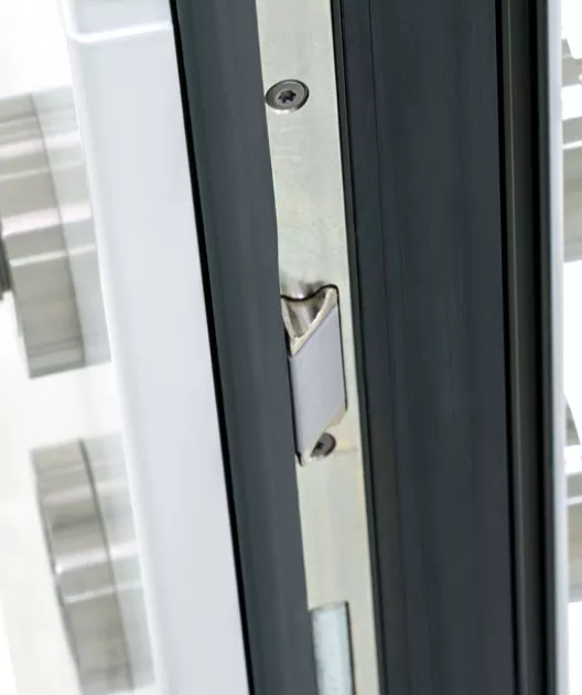 Serrure métallique argentée, encastrée dans une porte en verre noir, sécurisée et fermée, située dans un contexte moderne.