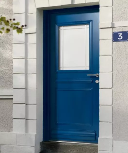 Porte bleue, fermée, entourée de pierres blanches, avec le numéro 3 affiché sur la droite, située dans un mur gris.