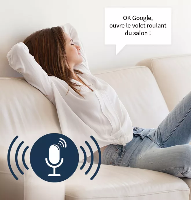 Une femme détendue, allongée sur un canapé, commande verbalement à Google d'ouvrir les volets roulants du salon.