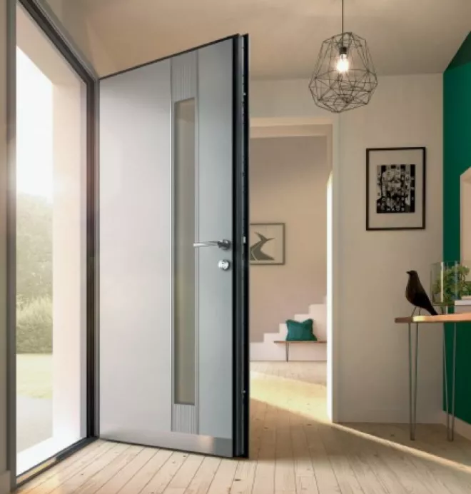 Porte grise ouverte menant à un intérieur moderne avec des escaliers, un cadre photo et une décoration élégante.